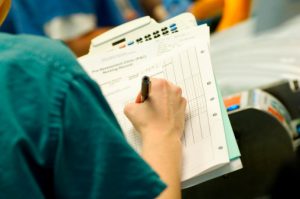 Surgical Nurse Writing On Patient Chart
