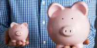 Man Holding Large And Small Piggy Bank